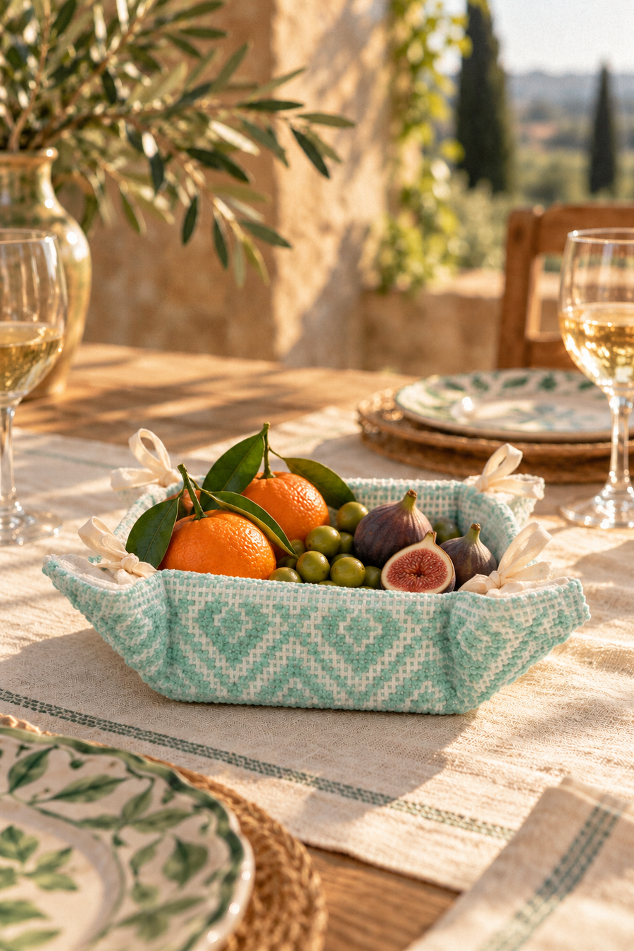 CESTINO Verde basket with oranges, figs and loose green olives on a Mediterranean table