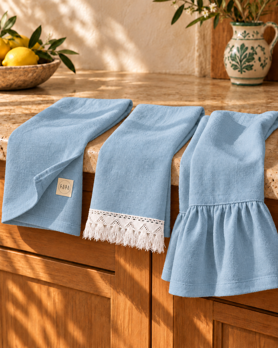 Three blue PANE linen towels with contrasting white fringe and CASA TOTO label in an Italian kitchen